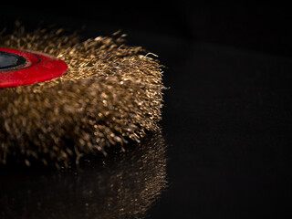 Circular wire brush for cleaning various surfaces. Grinding disc and Polished steel wire brush of a angle grinder. Black background. Low key photo.