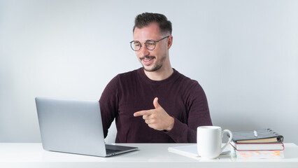 A man with glasses communicates via video call on a laptop, an online conference at work