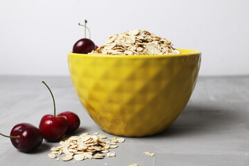 oatmeal oatmeal in a yellow plate bowl with cherry berries on a gray background. Proper healthy nutrition diet. delicious food