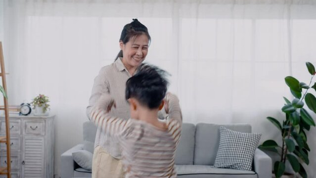4K, An Asian single mother and his son jumping hand in hand jumping in front of the sofa in the living room of the house happily and happily playing the naughty age of the boy.