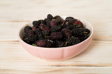Bowls with mulberry fruit on wooden table