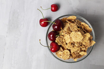 corn flakes with berries fruit cherries in a bowl plate on a gray background top view. Delicious healthy class breakfast Healthy food care for the door