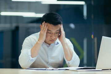 Stressed businessman holding face with his hands because having trouble. Bankrupt Asian Male is...