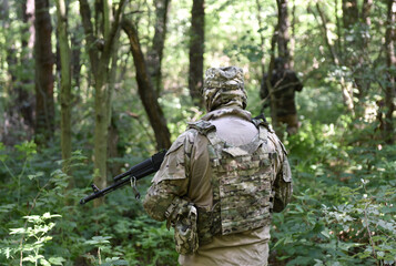 Soldiers with assault rifle in forest. Soldiers during combat. Tactical exercises. War in Ukraine - obrazy, fototapety, plakaty