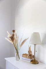 A bouquet of dry herbs and cereals, a wooden hare on a stack of books, two ceramic pumpkins and a...