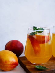 A glass of peach cocktail with ice, mint leaves on a gray background. Bar concept and summer drinks concept.