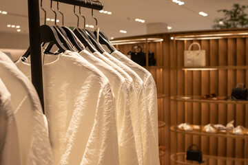 Women's beige long-sleeved t-shirts, on hangers. Defocused store background. Fashion concept.