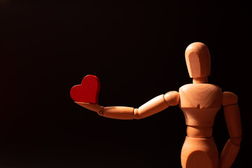 wooden mannequin holding a heart
