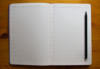 black pencil and diary on wooden table