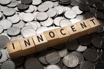 無実・潔白のイメージ｜「INNOCENT」と書かれたブロックとコイン
