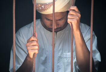 Religious muslim islam man in white session hold steel in jail on black background, concept for...