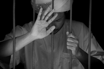 Religious muslim islam man in white session hold steel in jail on black background, concept for...