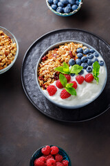 Bowl of granola with yogurt and fresh berries on a dark background. Healthy breakfast and various ingredients. Top view. Copy space