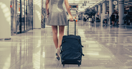 Blonde woman walks at the airport with her trolley - 523188061