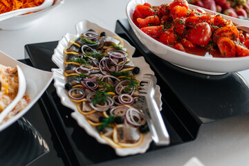 A fish fillet dish topped with fresh onions and greens, served on a stylish fish-shaped plate.