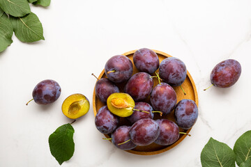 Fresh purple fruit plum on wooden plate light background top view