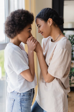 Side View Of Smiling African American Same Sex Couple Holding Hands At Home