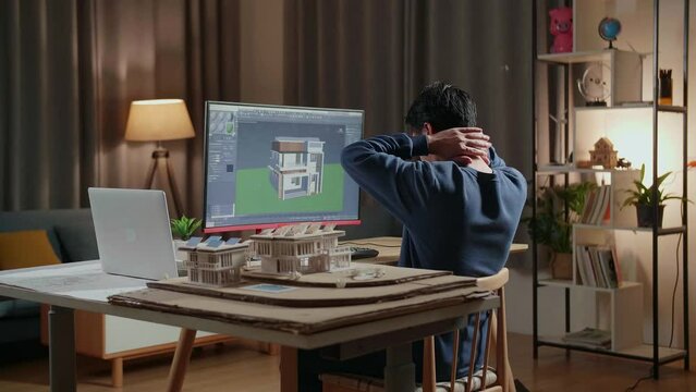 Asian Male Engineer Stretching While Designing House On A Desktop At Home. Cyber Games House Design And Decoration
