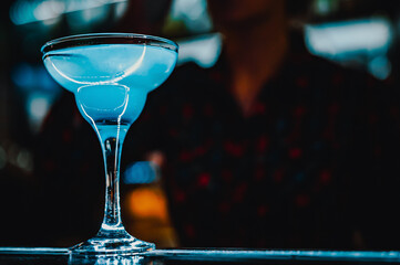 Blue lagoon cocktail with blue curacao liqueur, vodka, lime juice and soda on bar counter