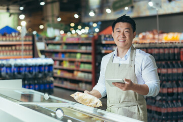 Portrait of Asian store manager, man with tablet checking expiration date of products, seller...