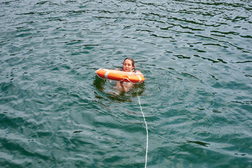 A Hispanic attractive young woman swimming in the water in a lifebuoy