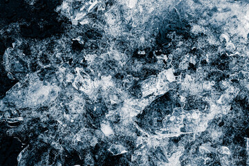 Crushed ice pieces on black background. Winter frozen background surface.