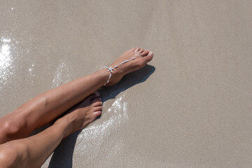 Girl sunbaths on the beach wearing an anklet - 523192410