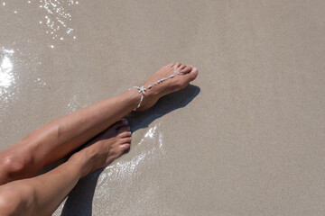 Girl sunbaths on the beach wearing an anklet - 523192436