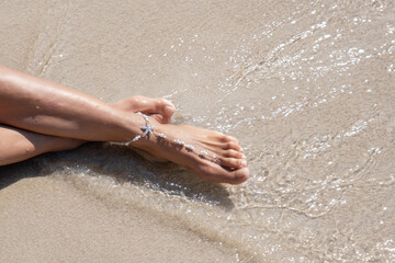 Girl sunbaths on the beach wearing an anklet - 523192867