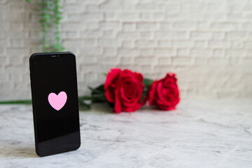ハートのあるスマホと薔薇と緑と大理石背景の左寄りの写真