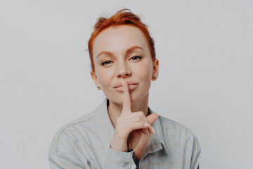 Caucasian female showing shh shush gesture, isolated on grey studio background