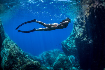 a girl swims underwater in apnea in the Mediterranean Sea
