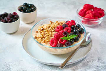 Glass bowl with oatmeal, different berries and crushed nuts in a glass bowl. Healthy balanced food