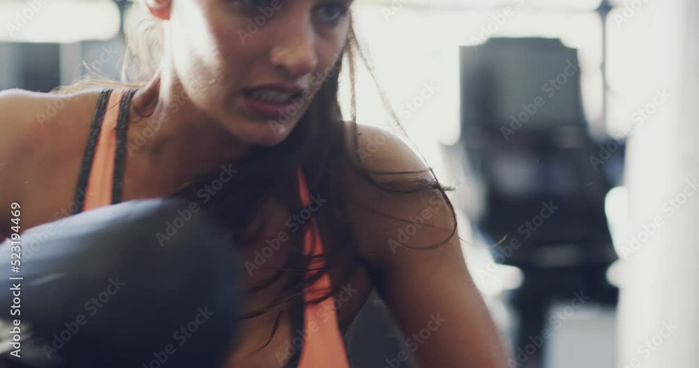 Wall mural Fit, angry and aggressive woman punching a boxing bag in the gym, exercising and focused on workout. A healthy athletic young female athlete training hard in fitness centre and getting toned.