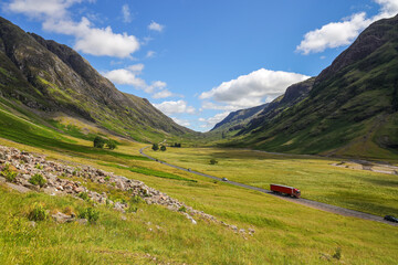 Fototapeta na wymiar The A82 road crosses pasture fields in the valley floor of Glen Coe. The A82 road crosses pasture fields in the valley floor of Glen Coe, under the mountains of the West Highlands of Scotland.