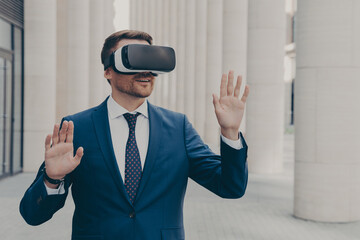 Surprised male office worker dressed formally stands outdoors in 3d goggles