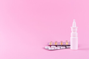 Medicines for the treatment of colds and viral diseases. White tablets, capsules, throat lozenges and nasal spray isolated on a pink background