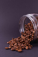roasted coffee beans spilled out of a glass jar. dark still life