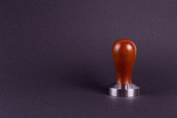 Coffee Tamper with Brown Wooden Handle. Top view on black background. Barman tool for pressing down ground coffee, a tamper for a coffee machine