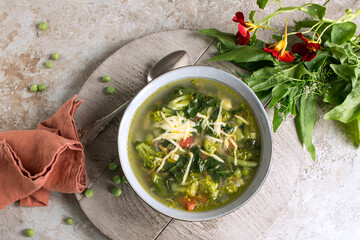 plate of minestrone soup with spinach and broccoli on a light table - obrazy, fototapety, plakaty