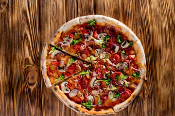 Vegan pizza with tomato sauce, cherry tomatoes, mushrooms, broccoli, red onion on woden background. View from above