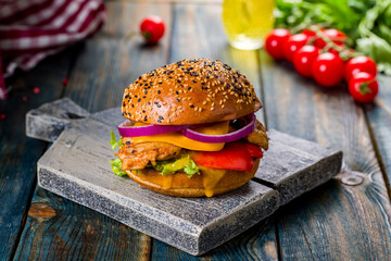 Burger with chicken, fresh vegetables and cheese on board