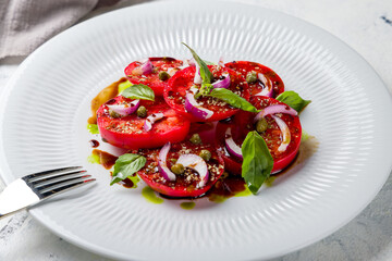 tomatoes bull's heart sliced with red onion on a white plate macro close up
