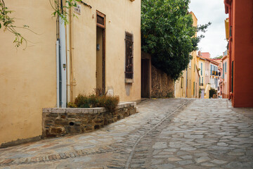 Naklejka premium Une vieille rue pavée dans un village de France. Une rue de Collioure. Des maisons colorées dans un village de Catalogne.