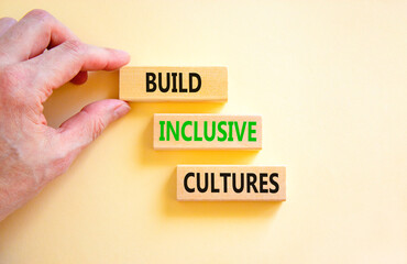 Build inclusive cultures symbol. Concept words Build inclusive cultures on wooden blocks. Businessman hand. Beautiful white background. Business build inclusive cultures concept. Copy space.