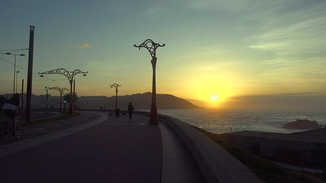 A Coru&ntilde;a promenade with people activity at sunset