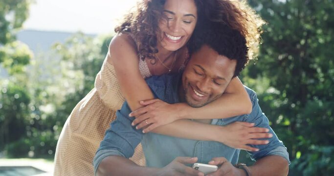An affectionate, happy and loving wife surprises her husband while relaxing outdoors in a park on a sunny day. Young and carefree African American couple bonding and enjoying the weekend together