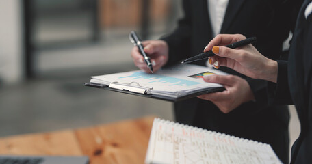 Image of businesswoman hand holding pen pointing at business document during discussion at meeting.