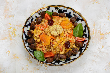 pilaf with meat, plum and apricot in a painted plate
