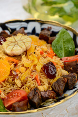 pilaf with meat, plum and apricot in a painted plate, macro vertical photo
